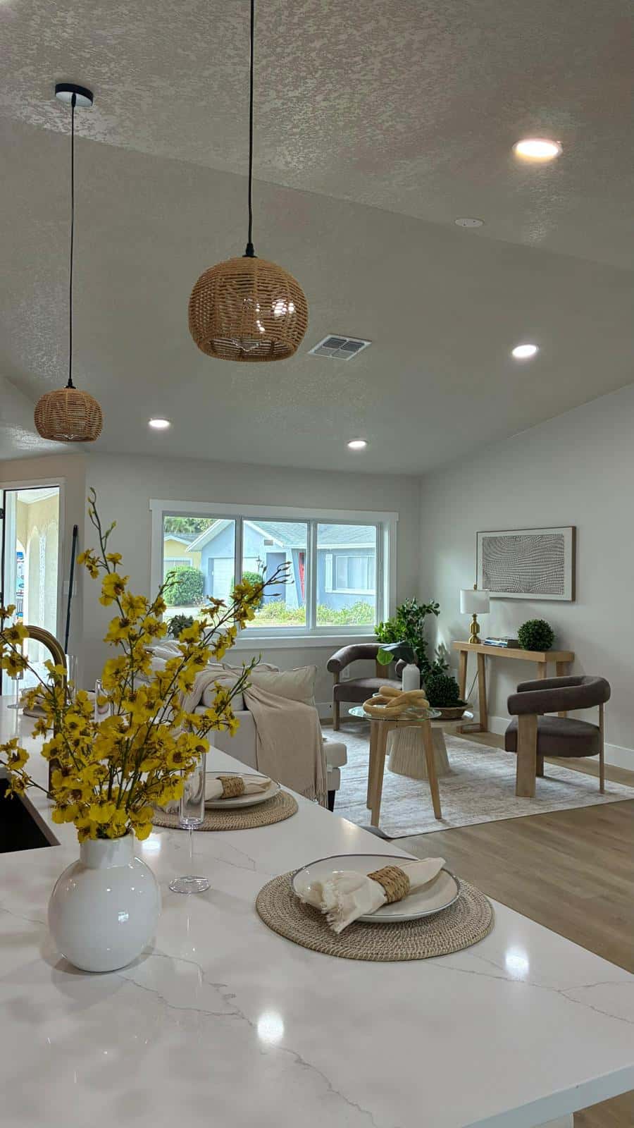 Freshly cleaned open-plan kitchen and living room with a marble island and warm wood floors in a Tampa Bay home