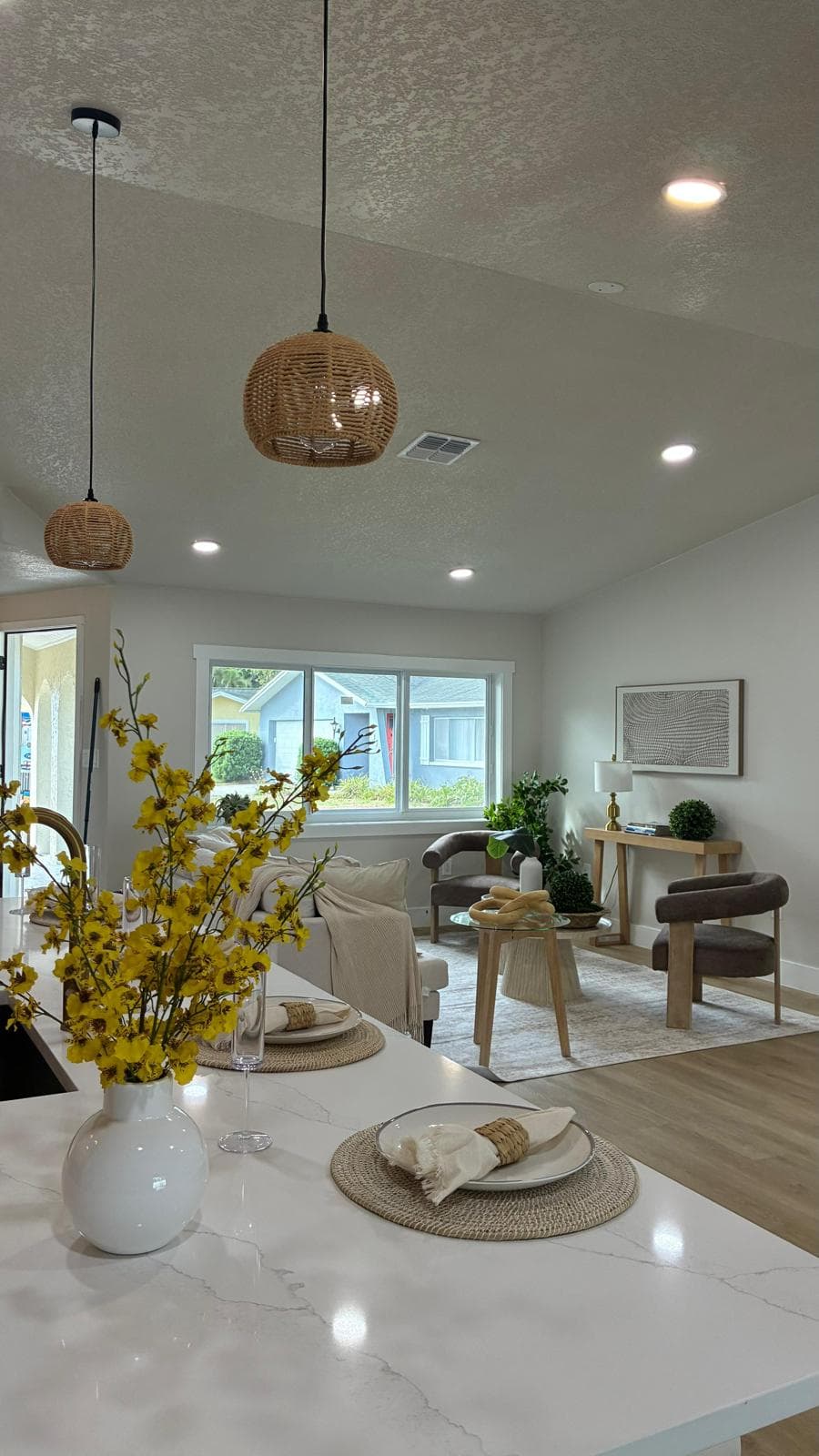 Freshly cleaned open-plan kitchen and living room with marble island and warm wood floors
