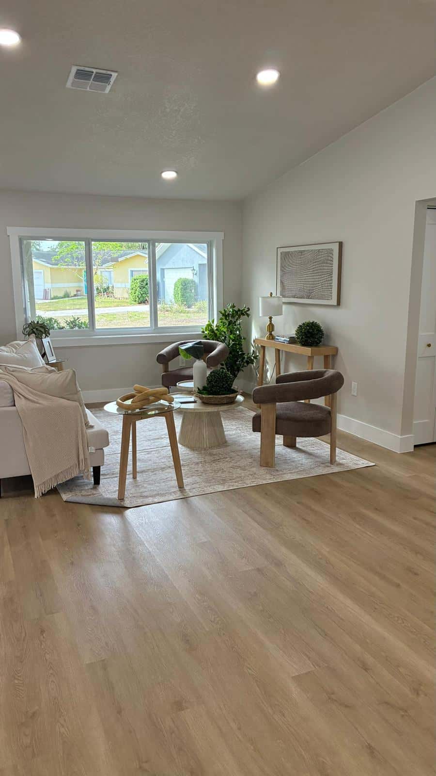 Bright empty living room with wood floors and a large window after a move-out clean